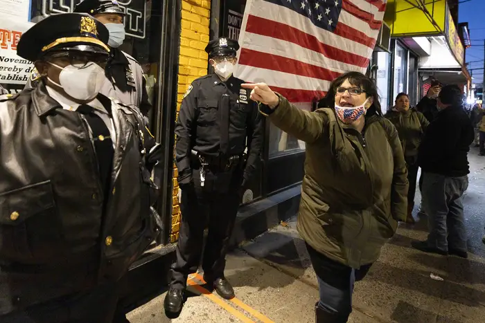A woman yells as New York City Sheriffs stand guard outside of the restaurant Mac's Public House at the start of a rally against state and city mandates to stop indoor dining to control the spread of the coronavirus, in Staten Island, New York, USA, 02 December 2020.